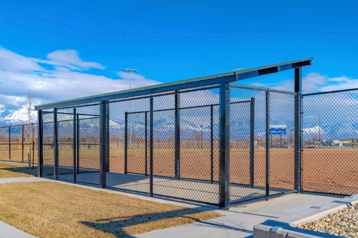 Baseball field dugout with slanted roof and chain link fence on a sunny day